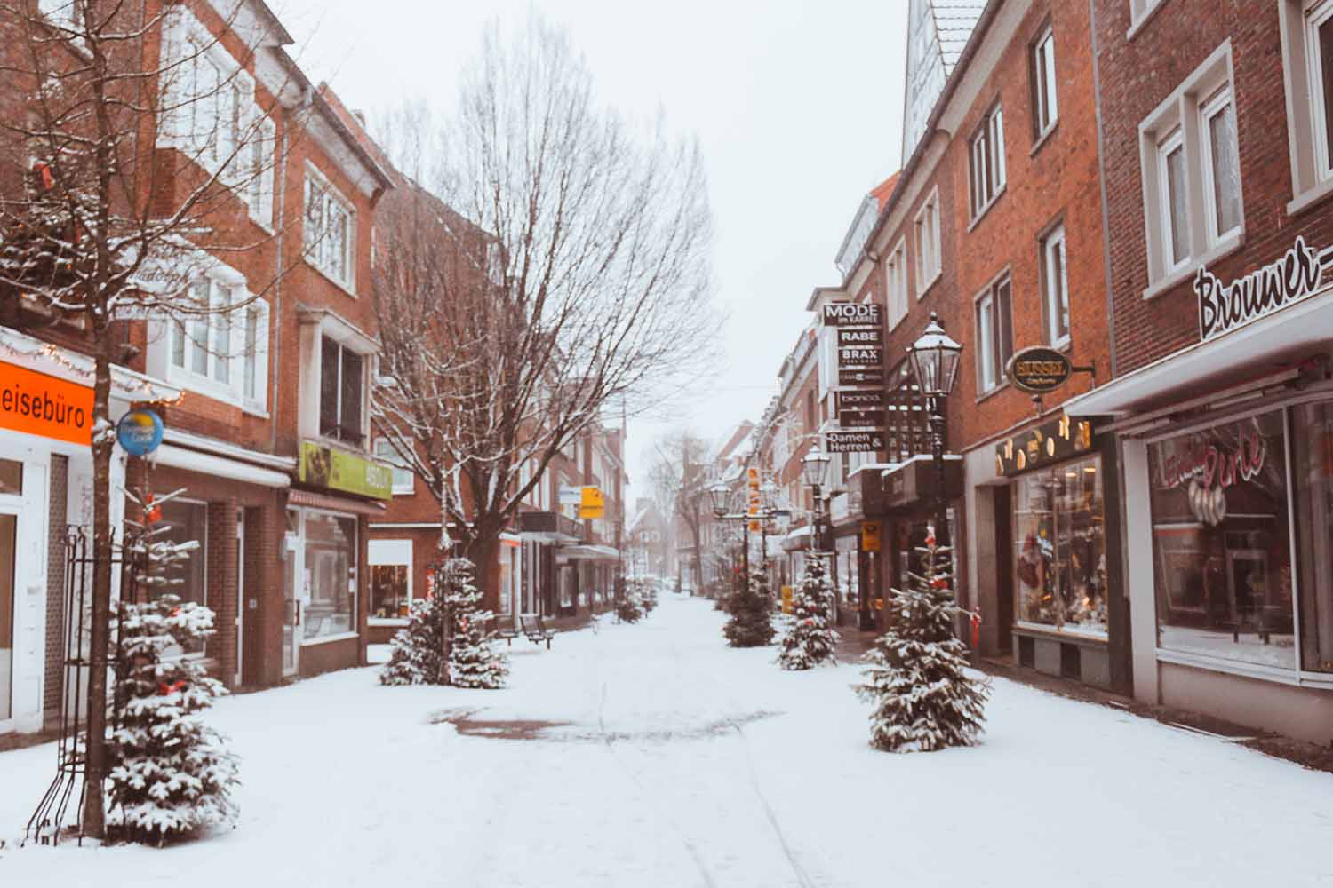 a snowy street with shops and trees